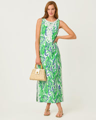 Woman wearing a green and white patterned dress holding a beige handbag on a white background