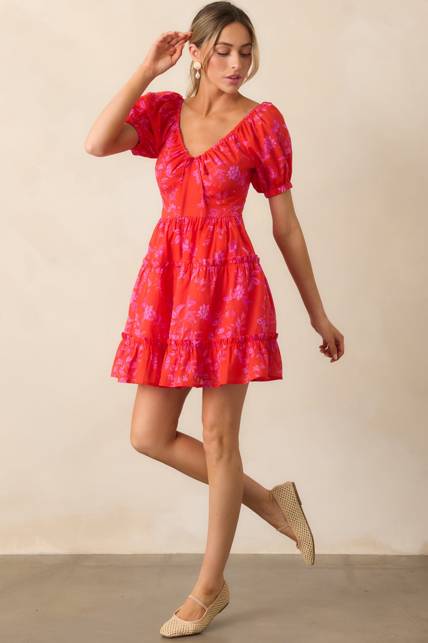 A vibrant red mini dress with a playful self-tie bow at the adjustable v-neckline, short puff sleeves, and a flowy silhouette.