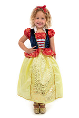 Child wearing a Snow White costume with a red top with gold swirl accents and a yellow skirt with gold foil floral accents on a white background.