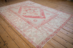 Corner angle of a vintage distressed Oushak carpet, highlighting its ivory field and red medallion.
