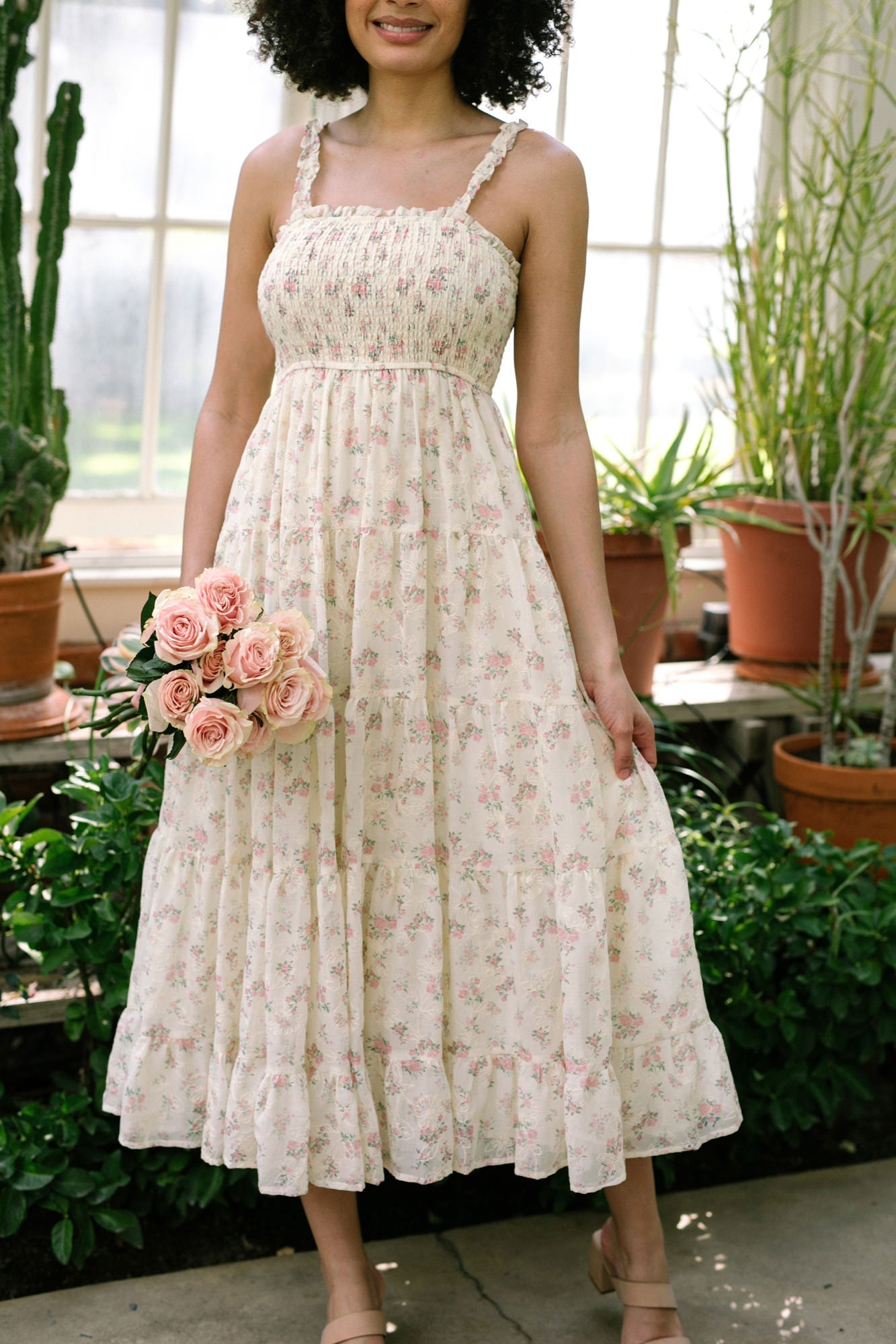 A floral-printed sleeveless midi dress with a smocked bodice, ruffled tiers, and adjustable straps in a soft, feminine color palette.