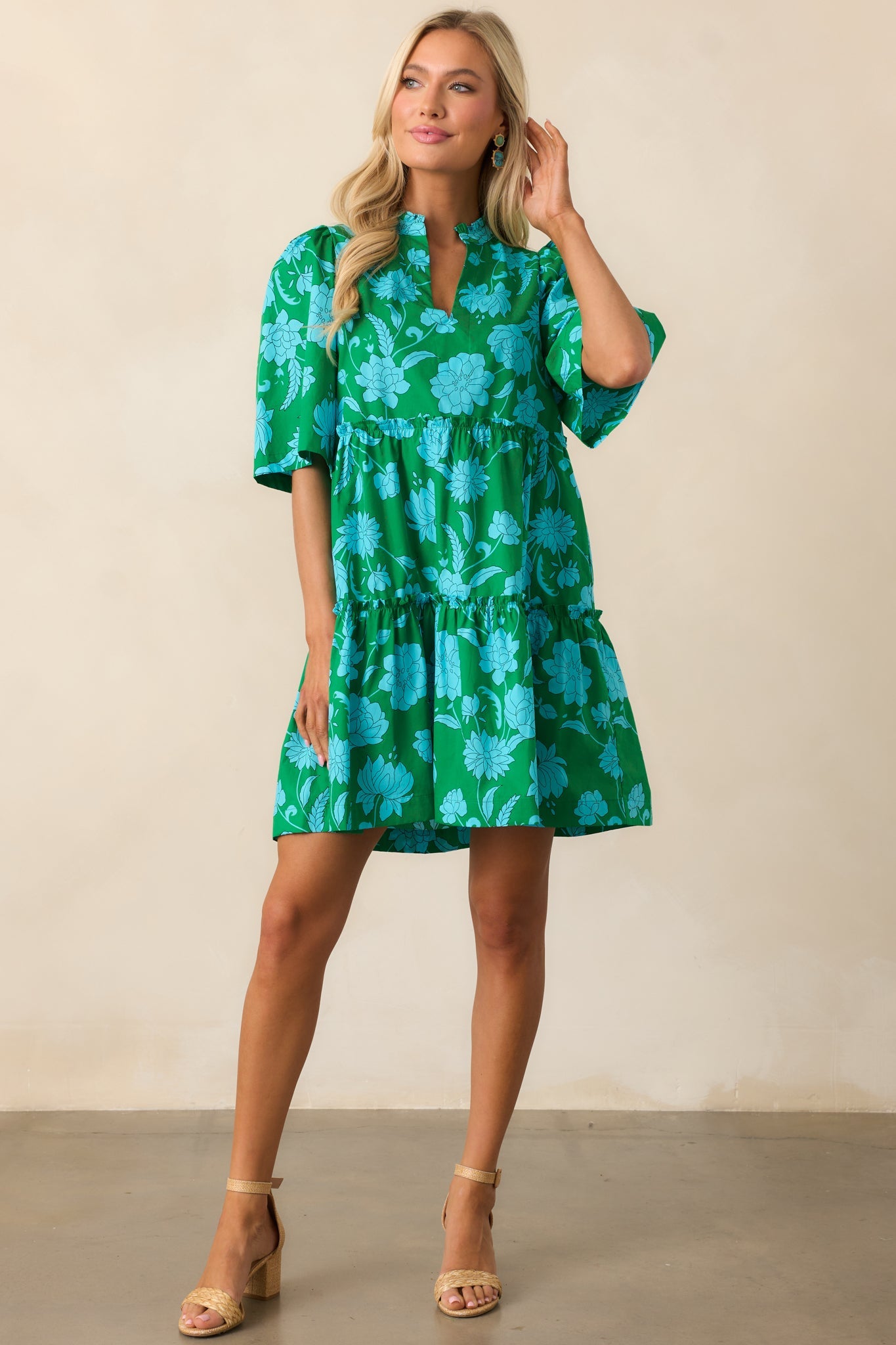 A green mini dress featuring half sleeves with a slightly puffed shoulder, a notch neckline, and a flowy silhouette.
