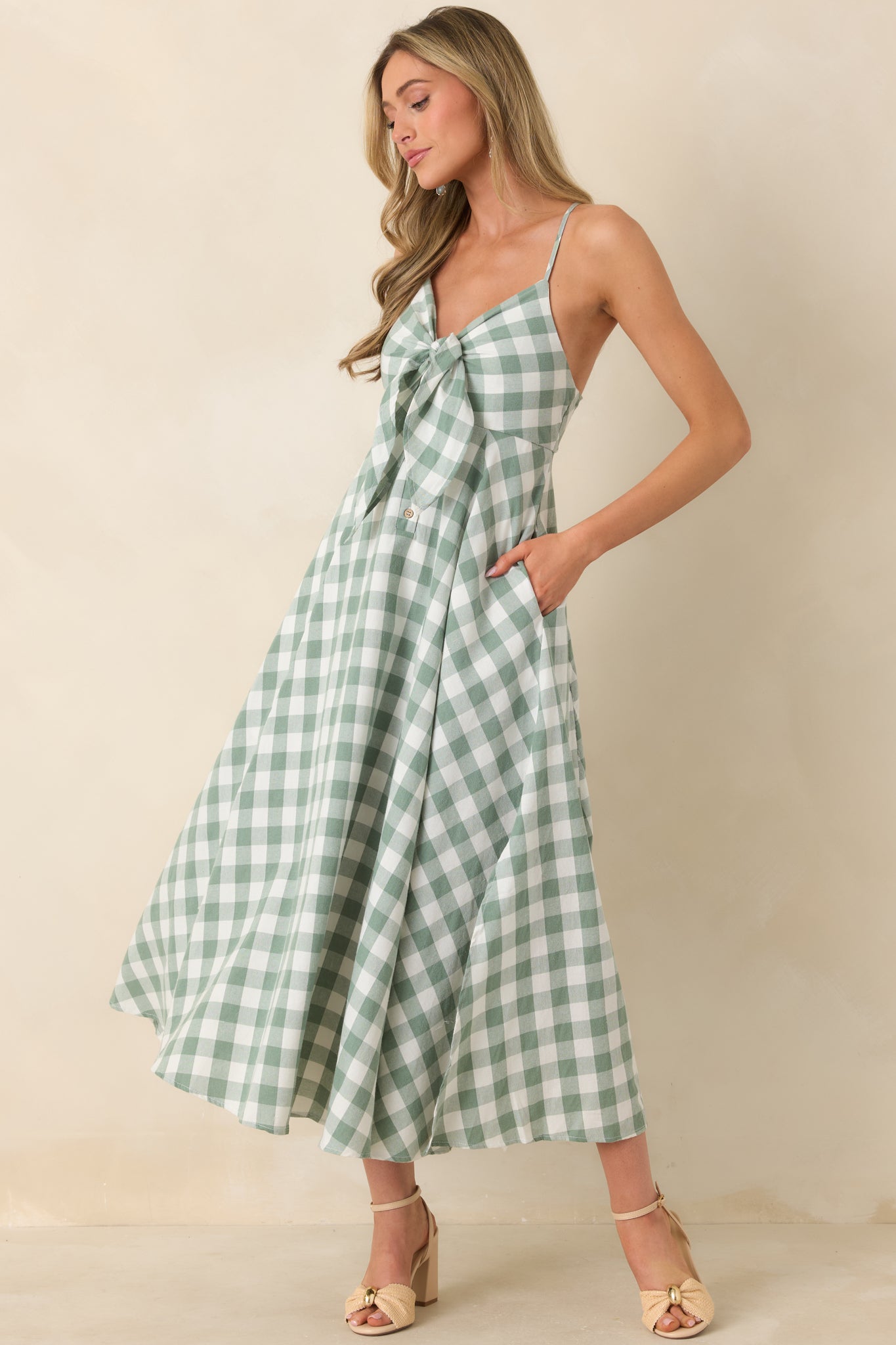 Midi dress with a flattering V-neckline, delicate front tie detail, and button accents cascading down the bodice, finished with a breezy skirt and subtle side slit for graceful movement.