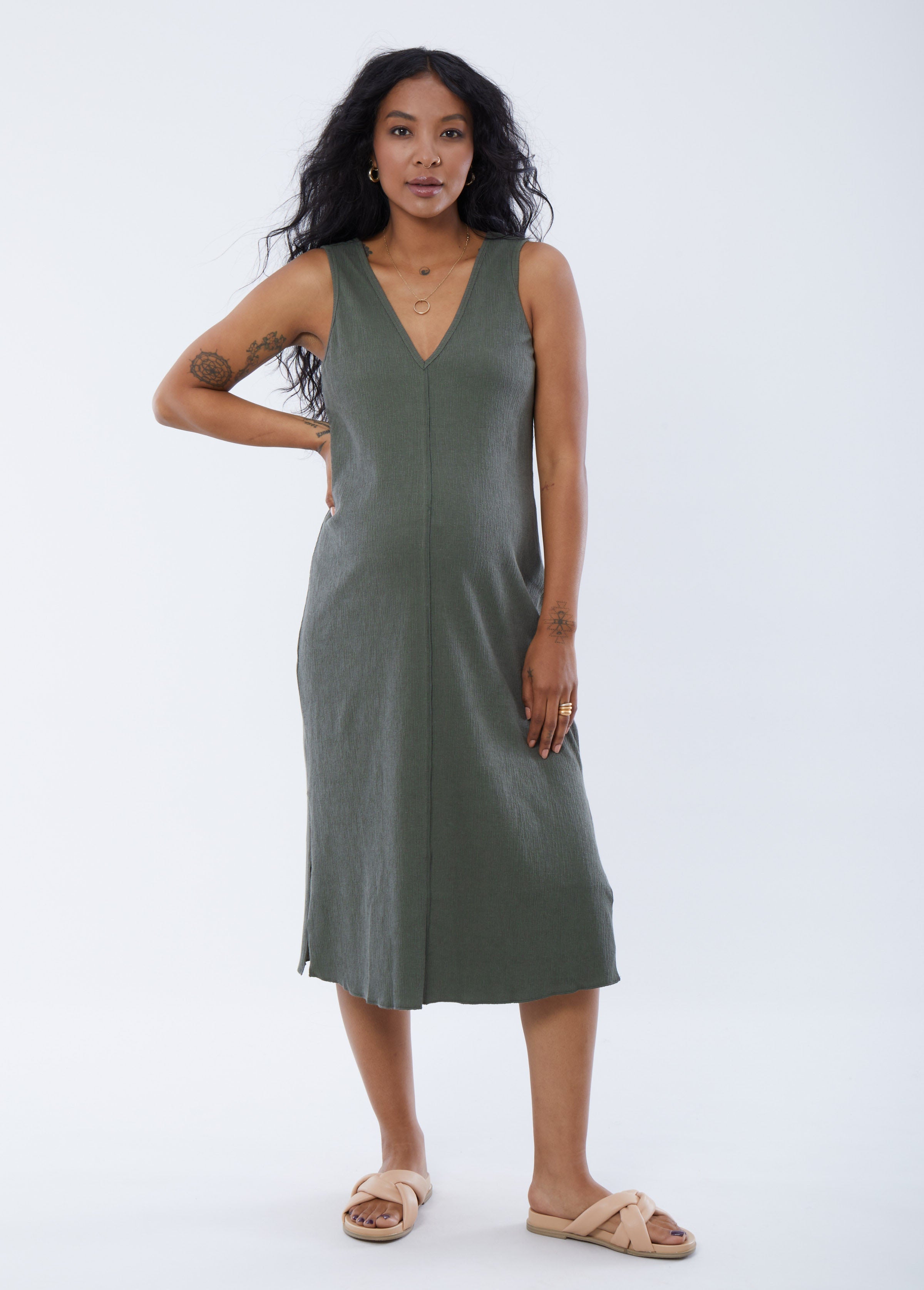 ||Pregnant woman wearing green v-neck sleeveless dress on a plain background