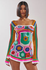 A woman with a sleek bob wears the CROCHET ALL DAY COLORBLOCK MINI DRESS, a vibrant crochet mini dress with bold geometric and floral patterns, posing against a plain light background.