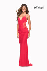 A woman smiles in a fitted, floor-length Backless Hot Coral Long Prom Dress by La Femme, featuring gold lace side detailing and beaded floral appliques. The La Femme logo appears in the top right corner.
