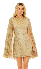A woman models the Mac Duggal 5931 Short Gold Beaded Cocktail Dress with cape sleeves, standing against a plain white background.