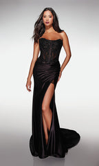 A woman models the Alyce 62011 long prom dress in black, featuring a strapless satin design with a sheer embellished bodice and thigh-high slit, posing against a light gray background.