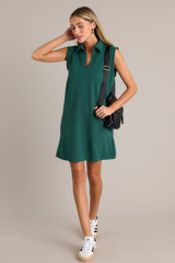 This green mini dress features a collared v-neckline, functional hip pockets, a relaxed fit, and a sleeveless design.