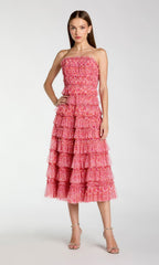 A woman stands in the Mac Duggal 8301—a yellow floral wedding-guest dress—against a plain light background.