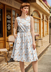 Woman wearing a light blue dress with floral pattern on a street in front of a café.