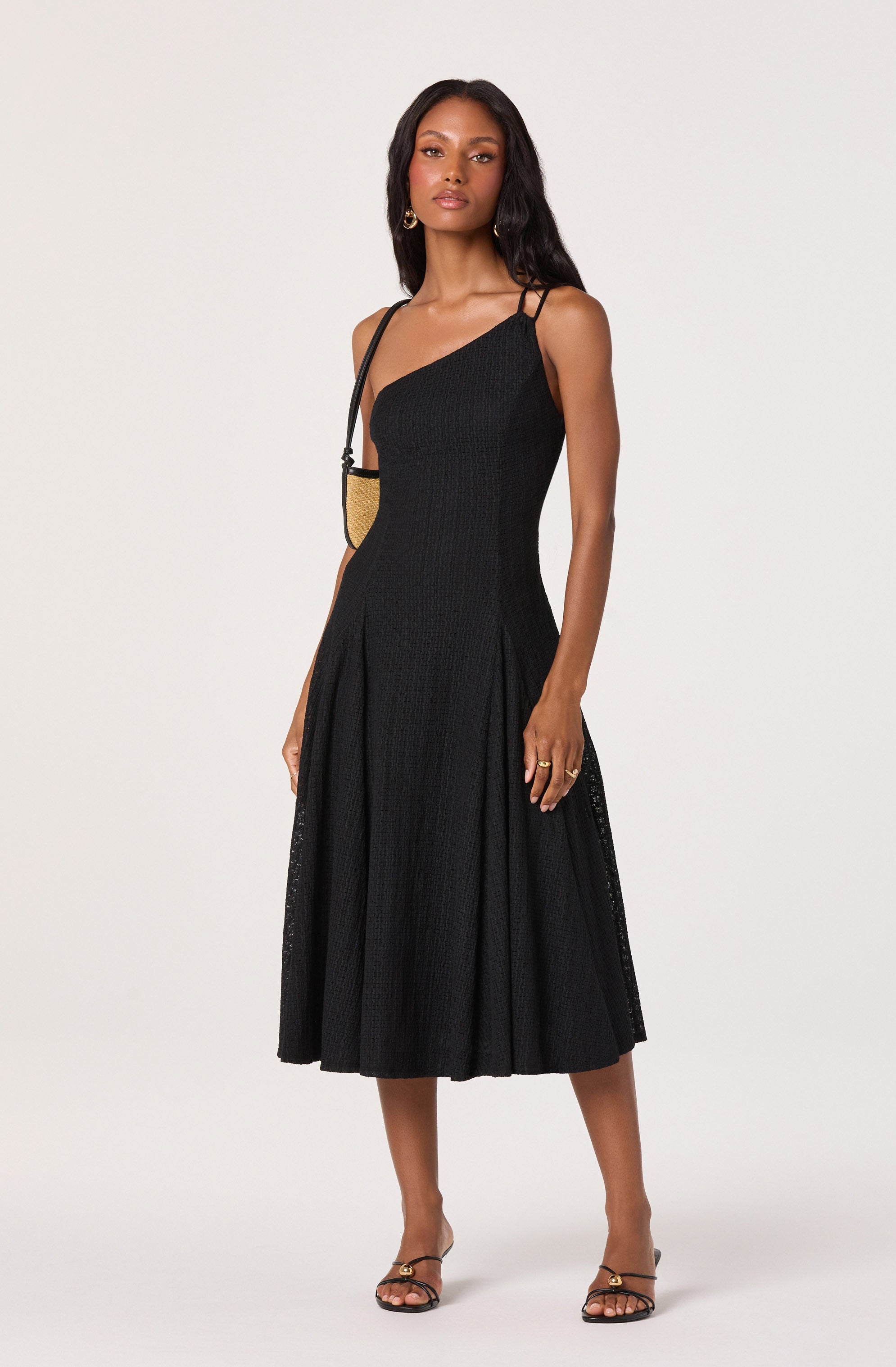 Woman in a black sleeveless, midi-length dress with thin shoulder straps.