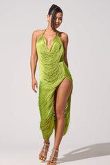 A woman wears the SOFIA FRINGE HIGH SLIT MIDI DRESS IN GREEN—a chartreuse party dress with fringe, deep neckline, and high slit—paired with strappy heels. She stands against a plain background, smiling with her hair tied back.