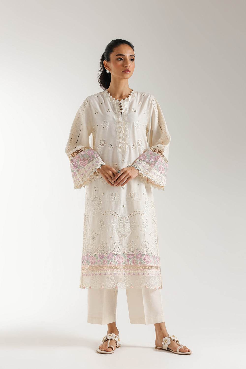 Woman wearing off white 2-piece embroidered Lelan suit with full sleeves and floral schiffli embroidery, paired with solid trousers