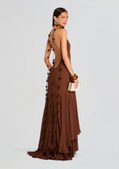 Brown Deena Chiffon Dress backless gown with strappy back and pom pom fringe, model holds a wooden clutch