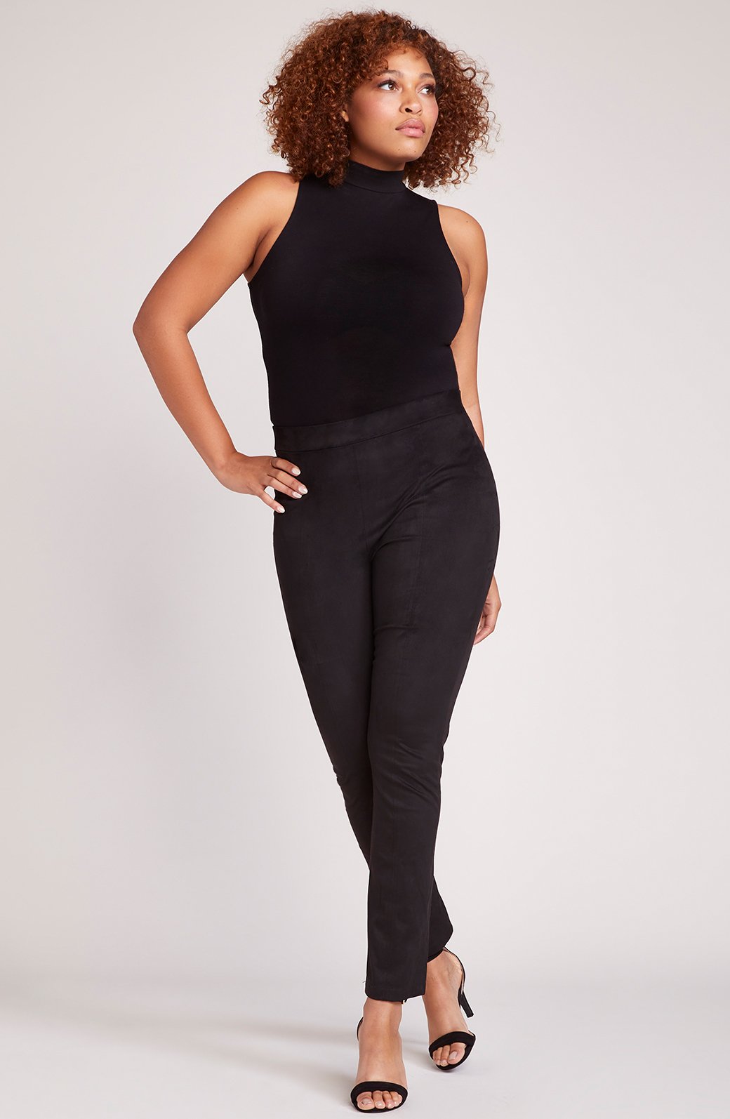 Woman wearing soft faux suede high-waisted leggings with stretchy fit, luxurious texture, versatile neutral bottoms for day-to-night style