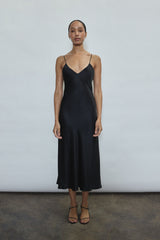 Front view of a model wearing the black sueded silk charmeuse Kamperett Caroline Midi Slip Dress with V-neckline and corded straps.