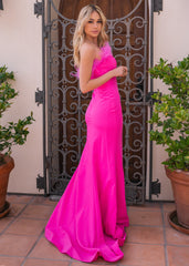 A woman stands gracefully, wearing a vibrant pink gown with feathered details. She poses near a wrought iron gate, surrounded by potted plants on a tiled floor.