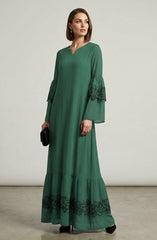 Woman wearing a green dress with lace details on a plain background