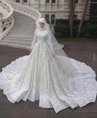 A bride posing elegantly in a luxury long-sleeve A-line Muslim wedding dress with intricate lace detailing and a matching bridal hijab.