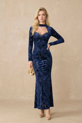 Front view of a navy floral velvet maxi dress featuring a lace-trimmed sweetheart neckline, long fitted sleeves, and a body-skimming silhouette, styled in a minimal studio setting.