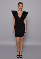 Model wearing the VSPR Joss Black Mini Dress with a plunging V-neckline, structured chic sleeves, and bodycon silhouette, standing against a neutral grey studio backdrop.
