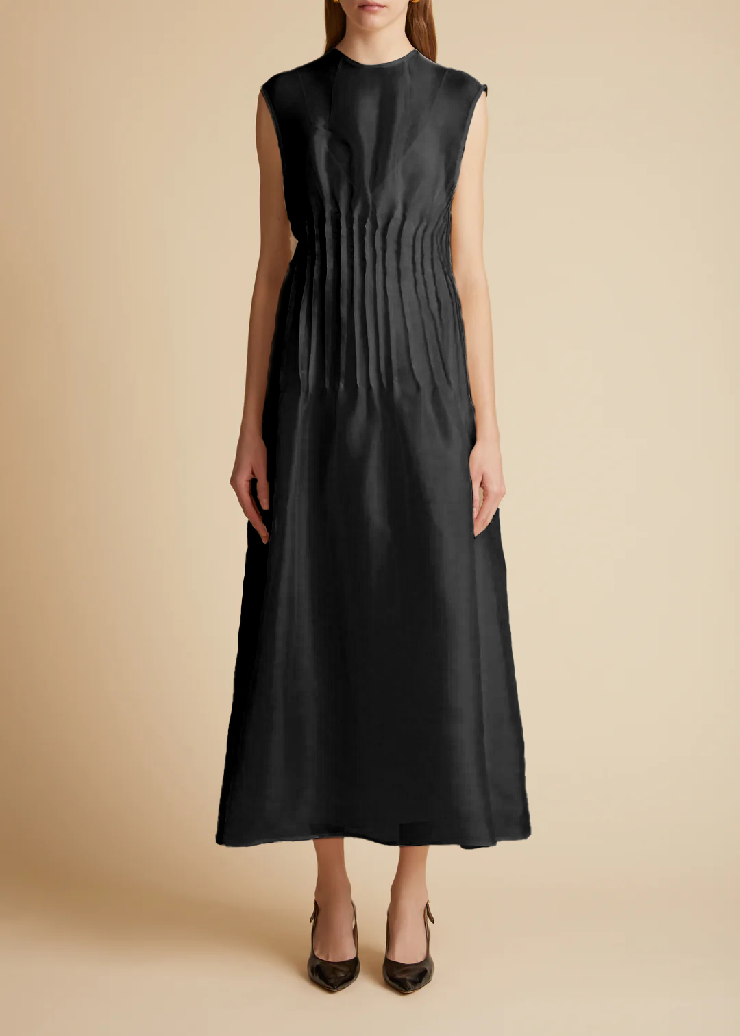 A sleeveless, black, maxi dress with pintuck detailing at the waist and covered buttons with a grosgrain guard. Includes a slip.
