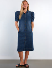 Woman wearing a blue denim dress with puff sleeves against a white background