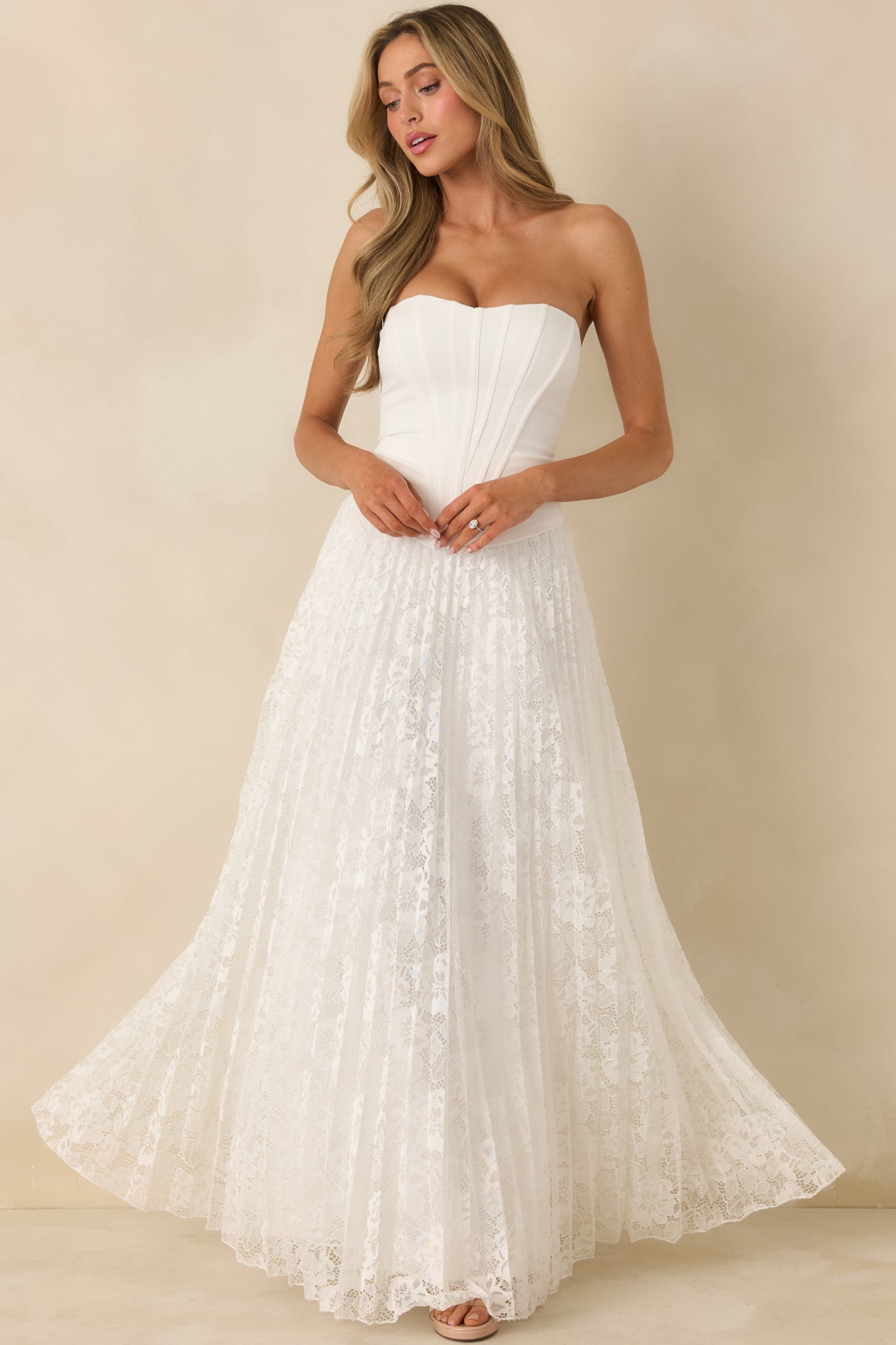 White strapless maxi dress with a structured corset-style bodice and flowing pleated lace skirt.