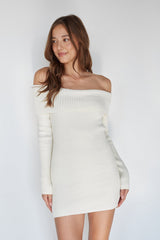 Woman wearing a white off-shoulder dress against a plain background