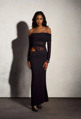 Woman wearing a black off-shoulder dress against a plain background