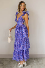 Full body side view of model wearing the Harlow Blue & Purple Floral Ruffle Midi Dress which features blue and purple sheer fabric, floral print, light purple metallic, blue lining, three tiered skirt, midi length, plunge neckline, adjustable ruffle strap