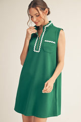 Woman wearing a green dress with white trim on a beige background