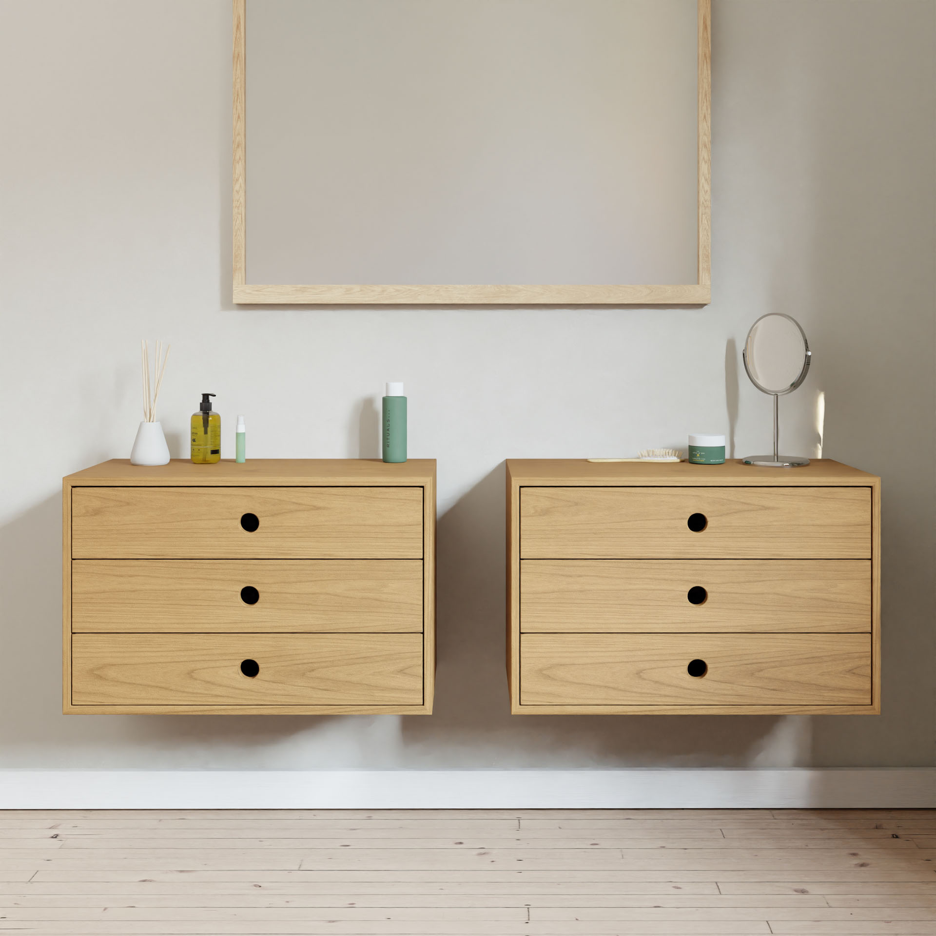 Two Krovel Hardwood Floating Dressers are mounted on a light wall below a large wooden-framed mirror; the left dresser stores toiletries, while the right holds a small round mirror and other items. The floor is light wood.#wood_cherry
