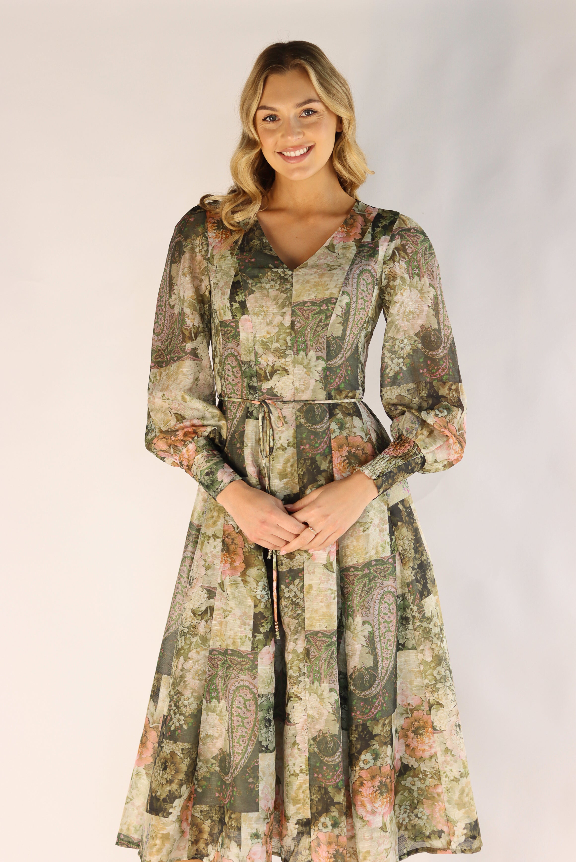 Woman wearing a long floral dress against a plain background