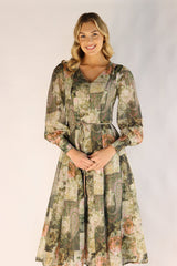 Woman wearing a long floral dress against a plain background