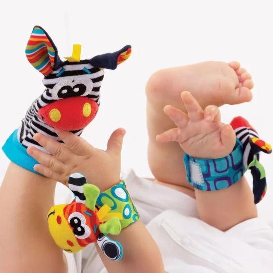 Un bébé est allongé sur le dos, les mains et les pieds levés, portant le Hochet pour Pieds & Mains - Jouet bébé éveil, des hochets de poignet et de pied colorés sur le thème des animaux, sur un fond blanc uni.