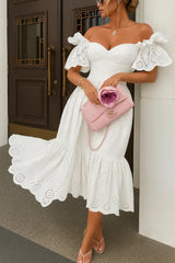 Model wearing the Kouvr Annie white eyelet midi dress on a balcony overlooking the ocean