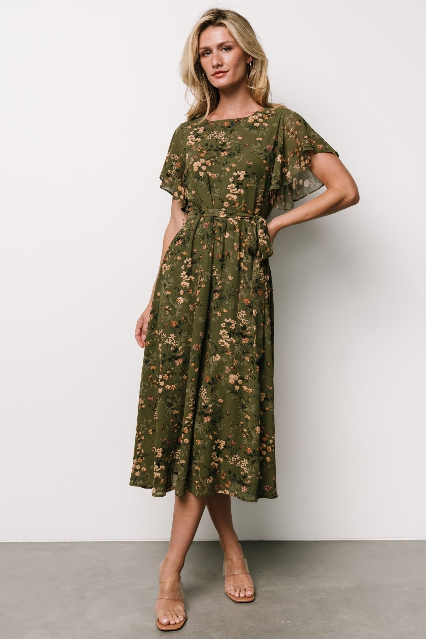 Front view of olive floral midi dress on mannequin showing round neckline, flutter sleeves, fitted bodice and flowy A-line skirt with ruffle detail.