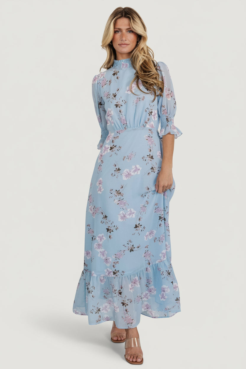 Front view of Marie Mock Neck Maxi Dress in sky-blue floral chiffon, showing smocked high neckline and single-tier maxi skirt with gentle drape.