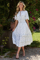 Front model view of white and sage floral boho midi dress with V-neck, smocked waist, and mid-thigh lining, shown on model.
