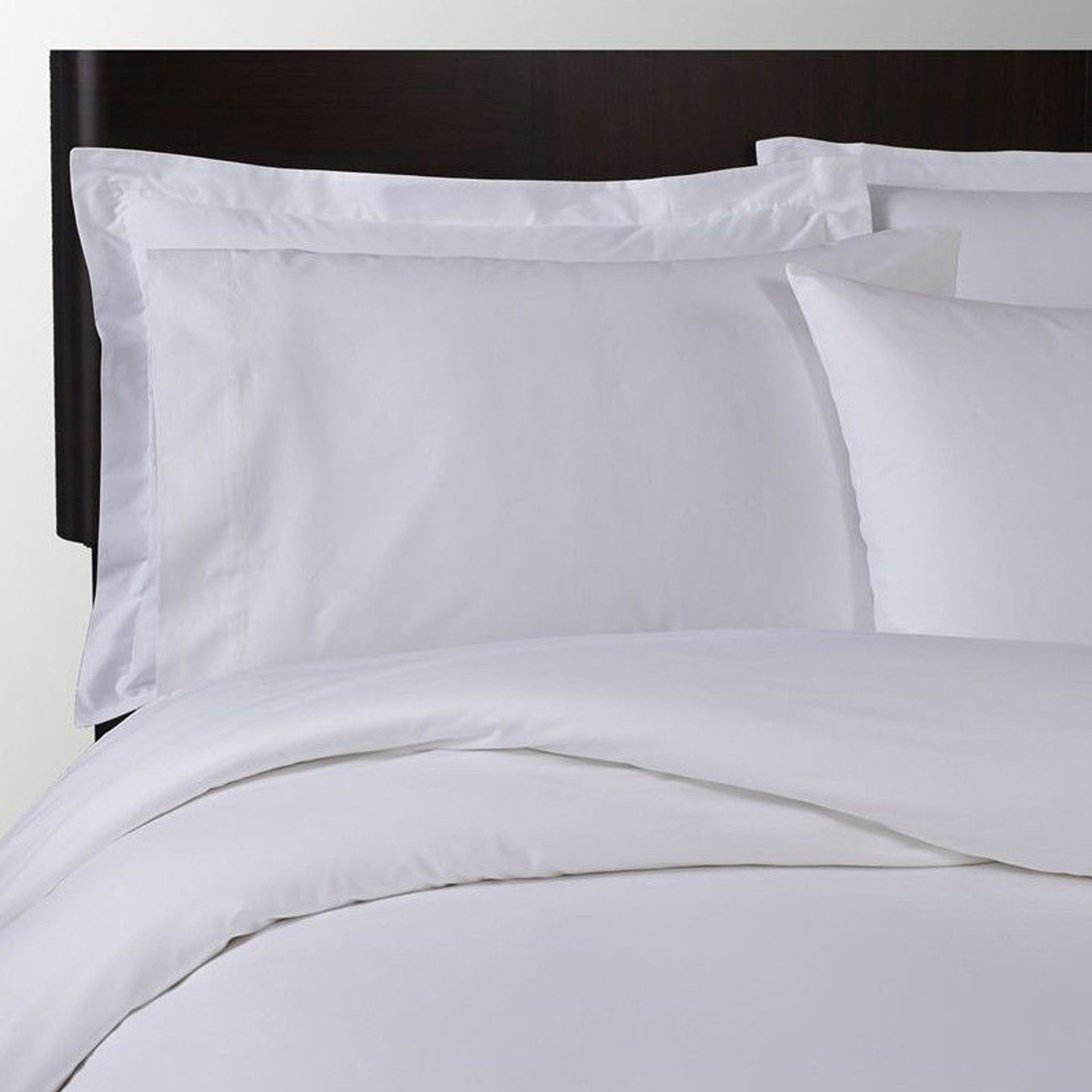 A neatly made bed with white pillowcases, sheets, and a comforter, all smooth and crisp against a dark wooden headboard—elevated by the luxurious Fitted Sheet Poly Micro Stripe T250 from 1Concier.