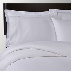 A neatly made bed with white pillowcases, sheets, and a comforter, all smooth and crisp against a dark wooden headboard—elevated by the luxurious Fitted Sheet Poly Micro Stripe T250 from 1Concier.