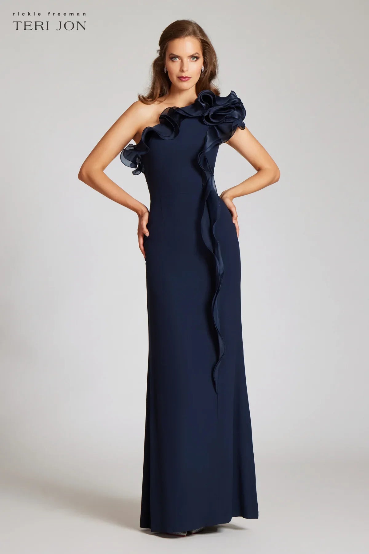 Teri Jon 249043 one-shoulder gown featuring a cascading ruffle detail and fitted silhouette. Perfect for formal evenings and mother of the bride or groom. Model is wearing the dress in the color navy.