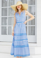 Woman wearing a blue and white striped dress with a wide-brimmed hat outdoors.