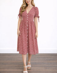 Woman wearing a red floral Tie Sleeve Button Front Midi Dress against a plain wall.