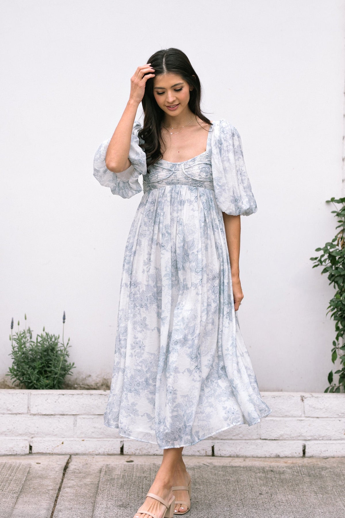 A soft floral-printed midi dress with billowing sleeves, a fitted bodice, and a flowing, ankle-length skirt in a serene blue and white color palette.