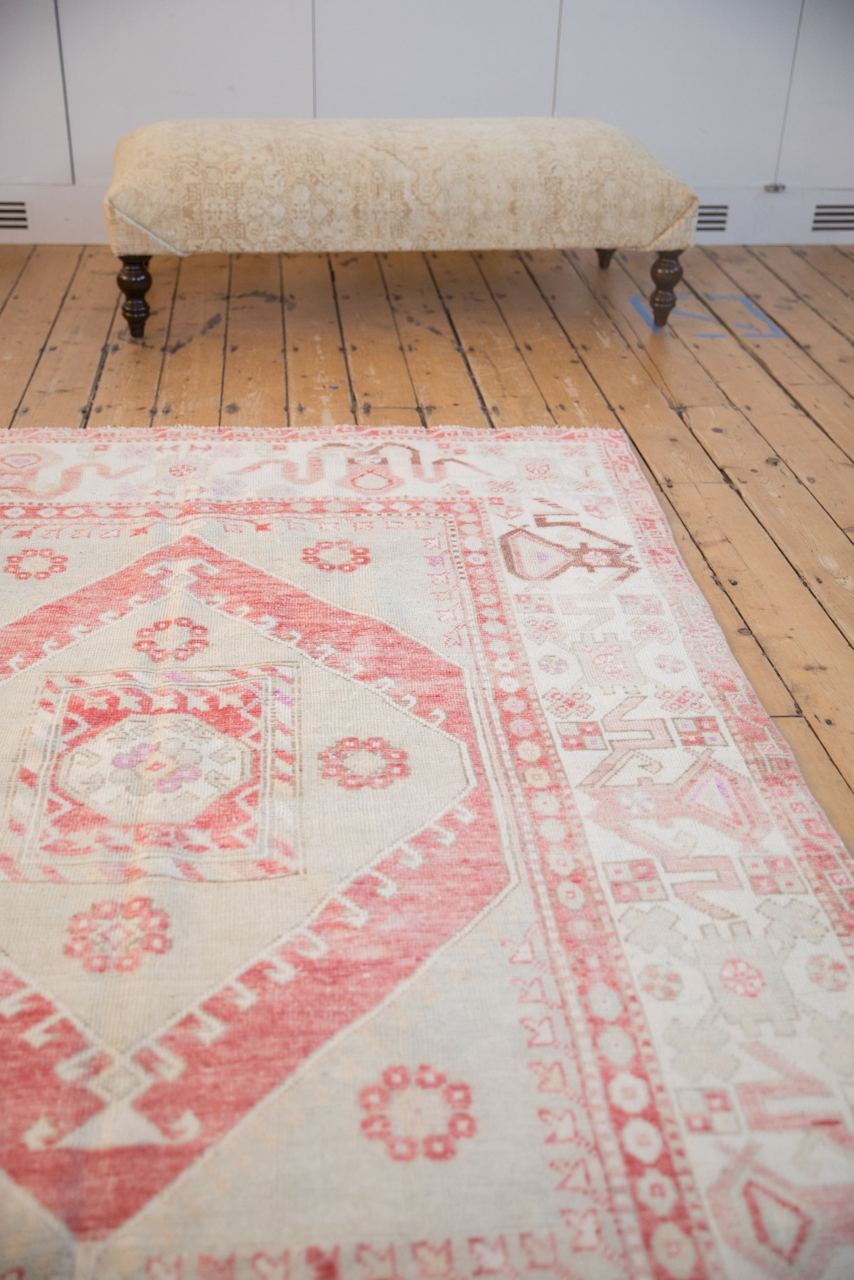 Distressed Oushak carpet with cherry red and ivory patterns styled in a room setting.
