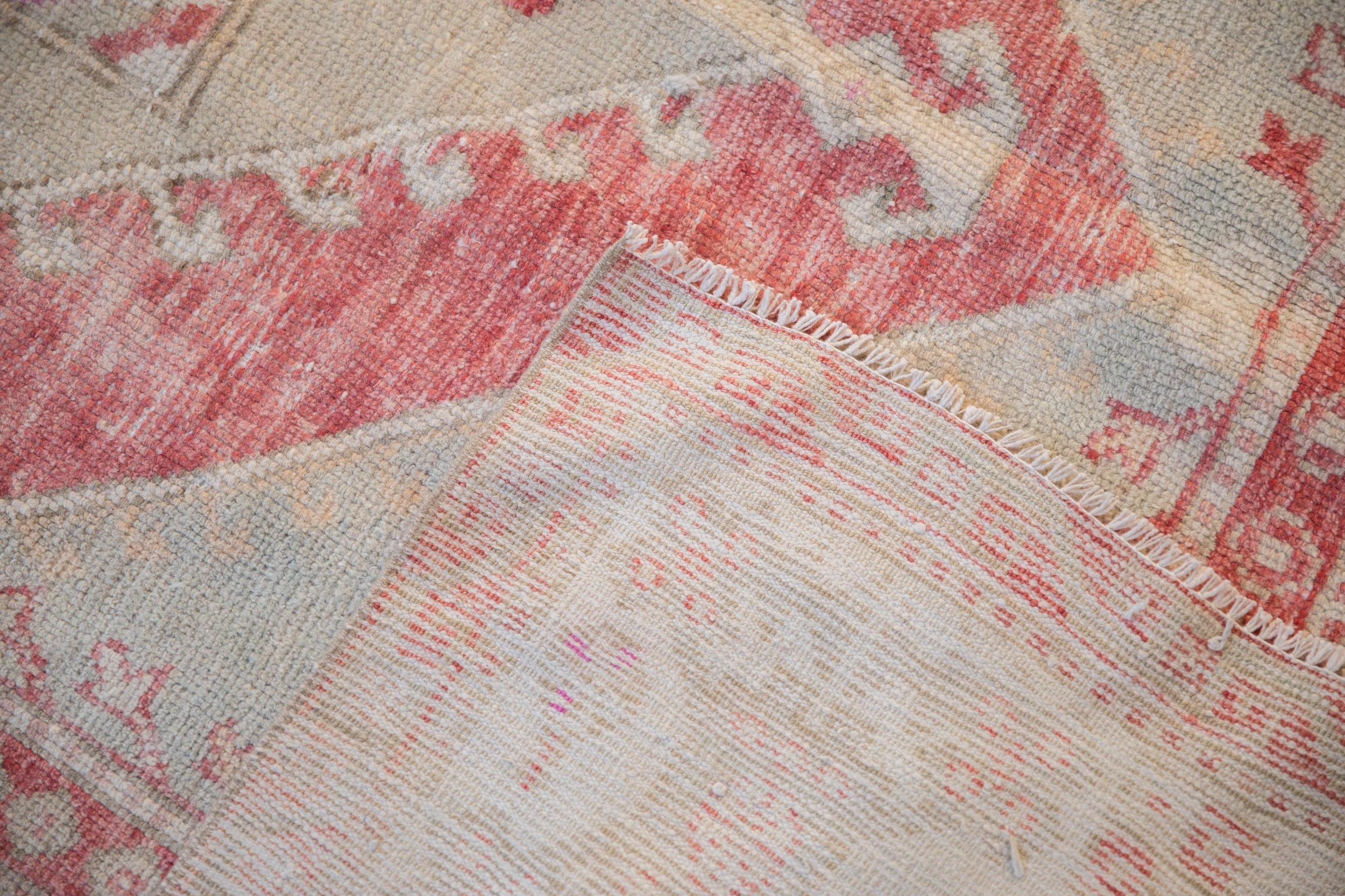 The hand-knotted foundation and secured side selvage of a vintage distressed Oushak rug.