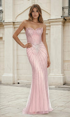 A woman stands outdoors in front of a light-colored building, wearing the Strapless Rose Pink Long Prom Dress L609 featuring a sheer structured bodice and beaded embellishments.